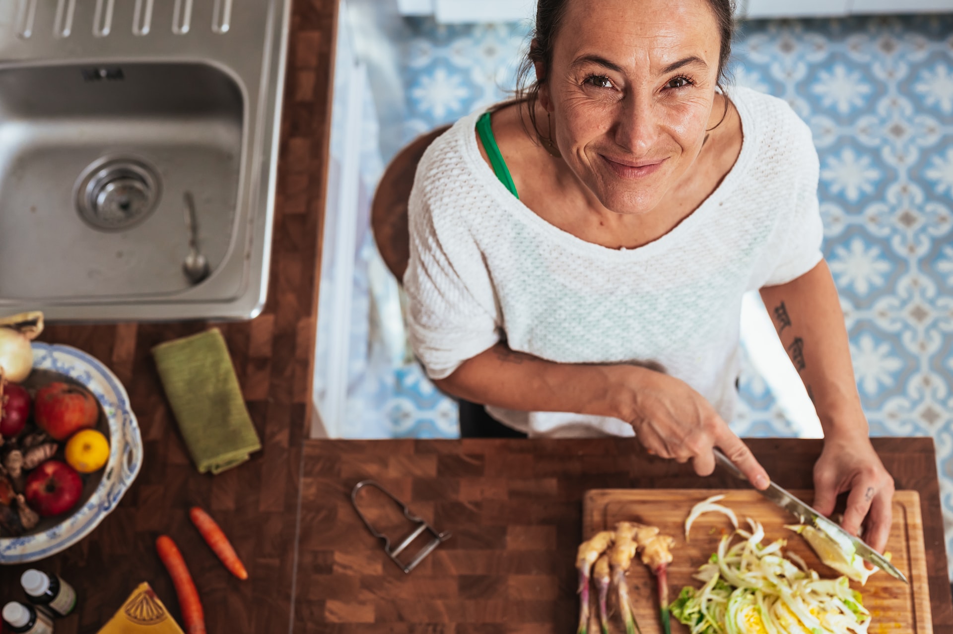 woman in white scoop neck shirt holding brown wooden chopping board